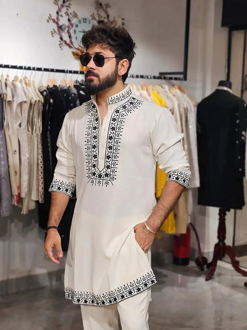 White embroidery kurta with black thread work and matching pajama set by Pravohammenskurta, displayed on a hanger.